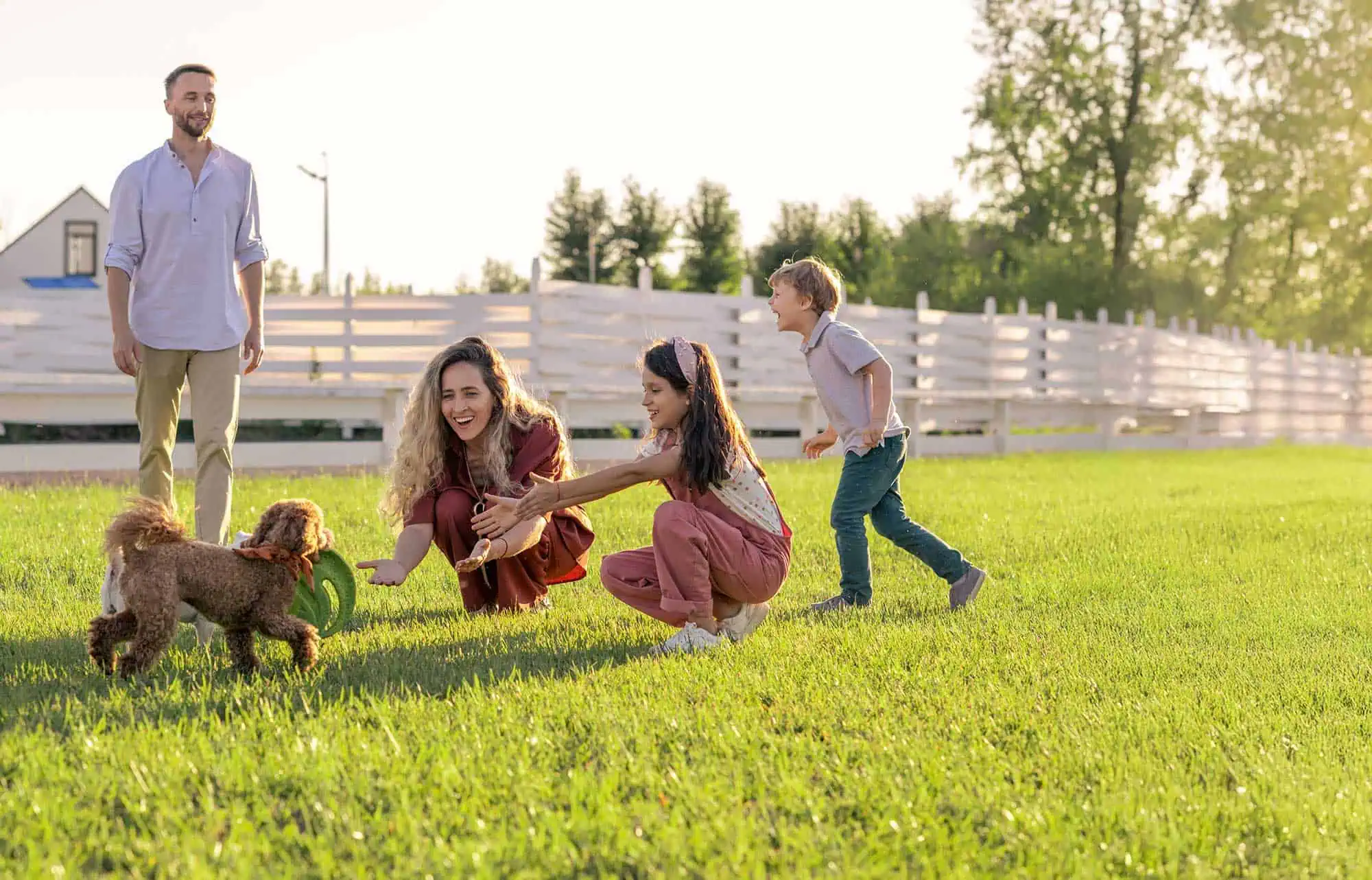 Family playing outdoors with their happy, healthy dog